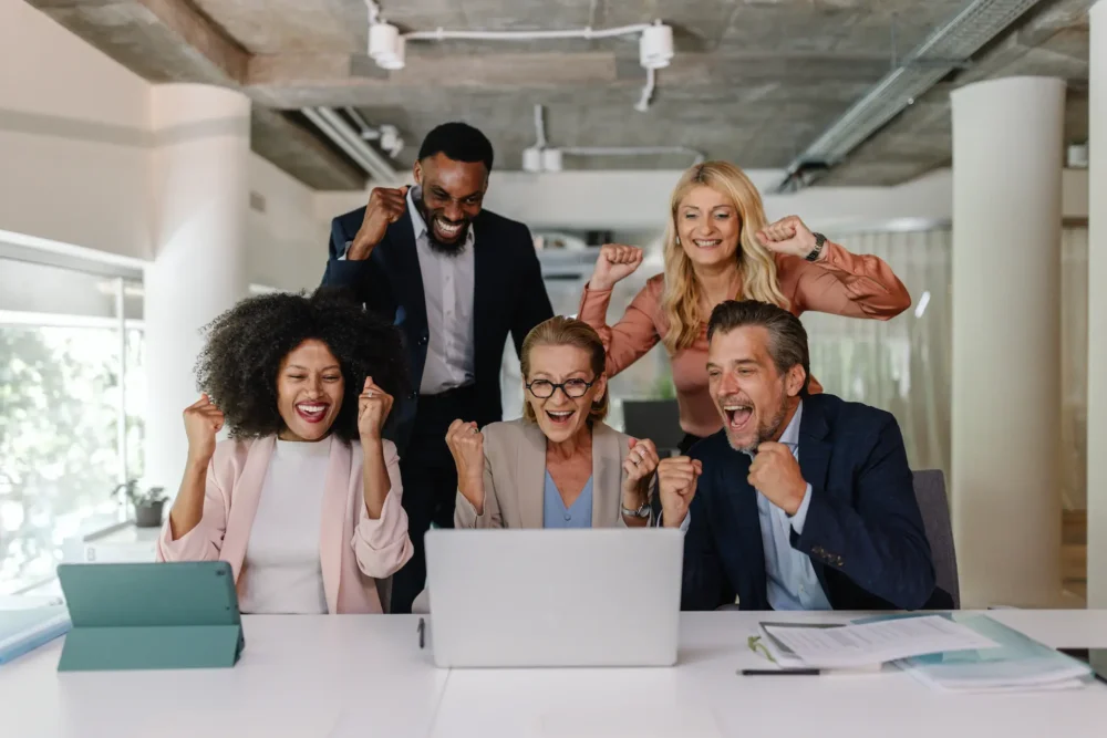 A dynamic group of diverse professionals exuding joy and excitement as they celebrate their achievements together in a vibrant office environment, emphasizing teamwork and shared success.