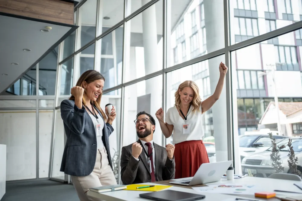 Excited business team celebrating success in modern office
